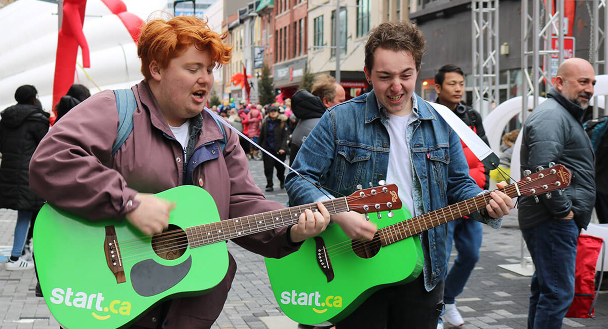 2 boys playing Start.ca branded guitars