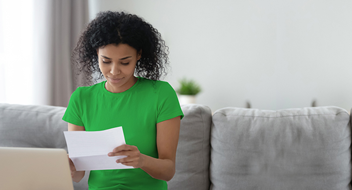 woman sitting in green shirt staring at her bill