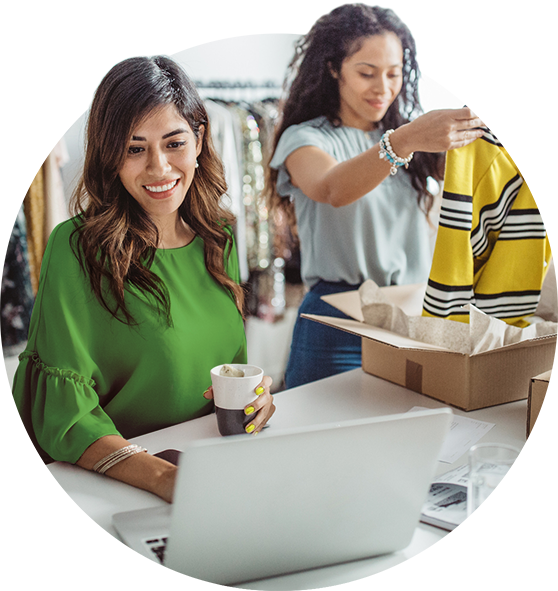 Two women in clothing shop on a laptop