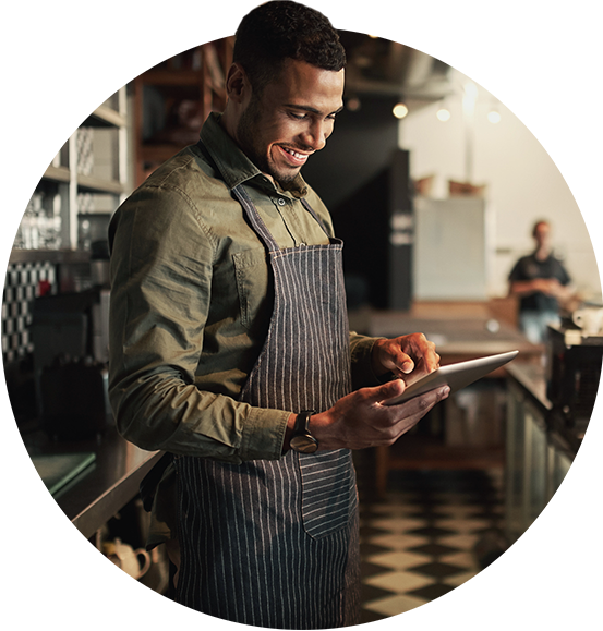 Business owner smiling while looking at his tablet and learning about fiber internet options for his restaurant