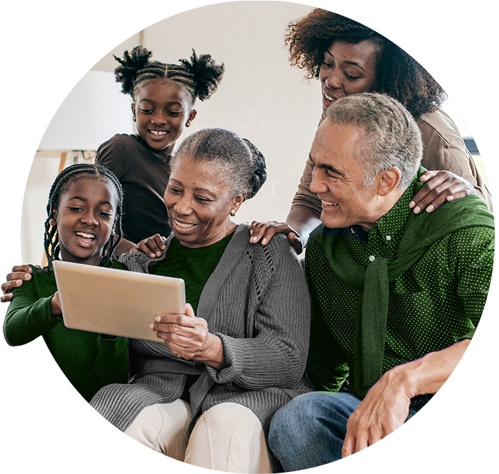 family of two girls with one woman and an elderly couple looking at laptop screen