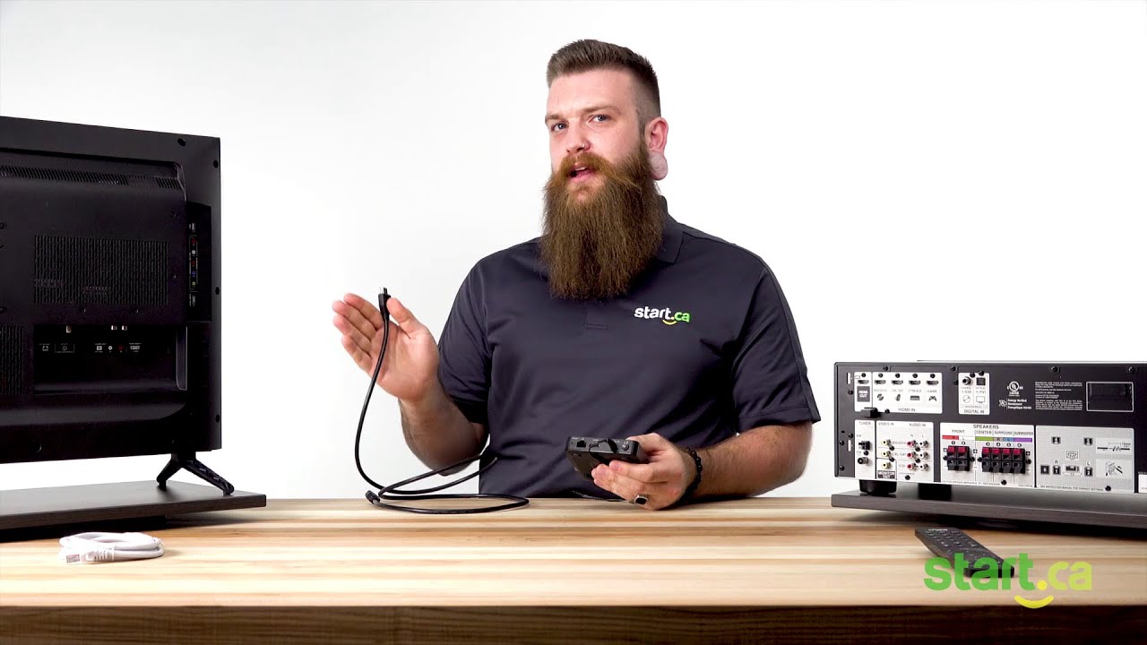 Employee is holding equipment and gesturing with cable in hand to show how to set up hardware