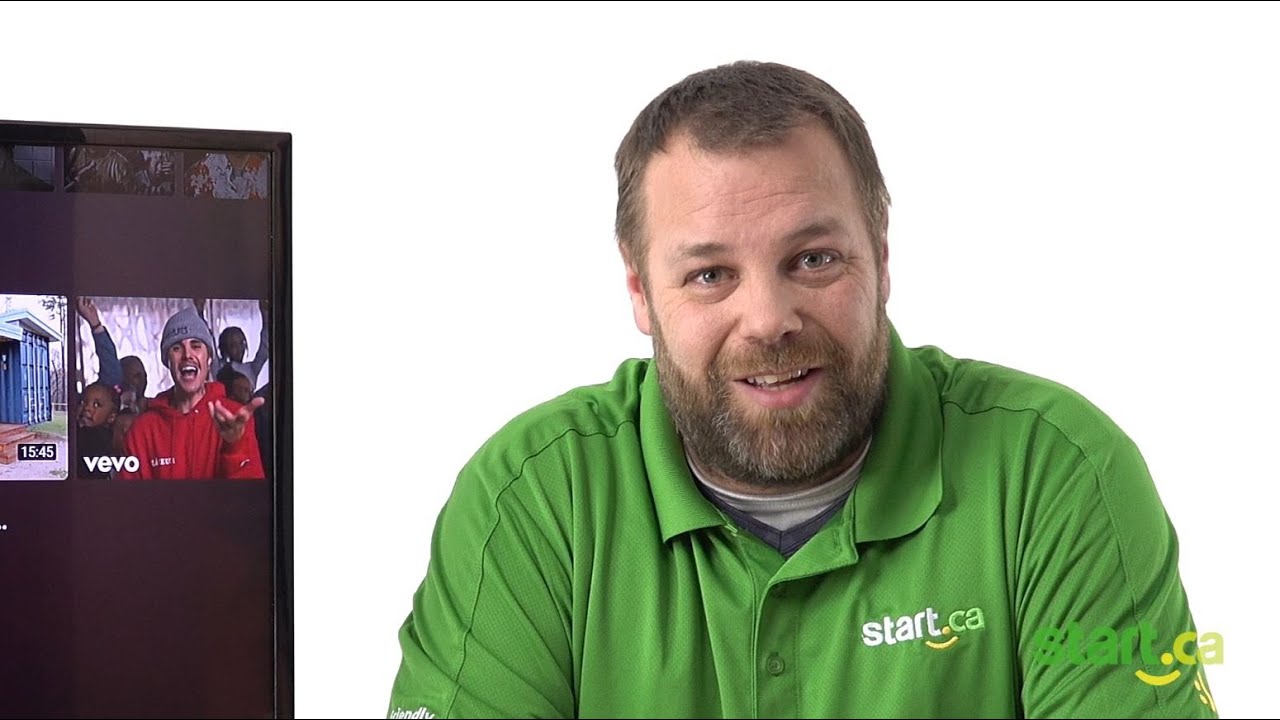 Support technician looking at camera smiling next to a TV that has Justin Bieber